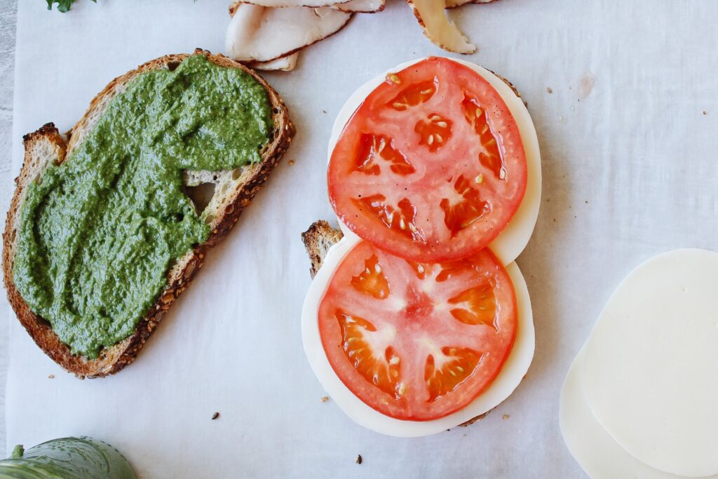 two slices of bread, one with pesto and one with tomatoes