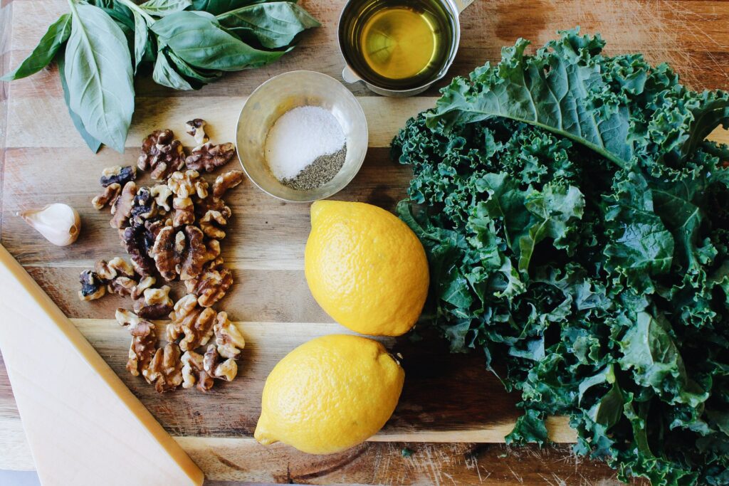ingredients for walnut kale pesto on a wooden cutting board