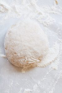 ball of homemade pizza dough on a floured surface