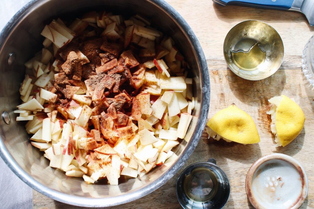 diced apples in a pot with cinnamon, lemon juice, maple syrup and water