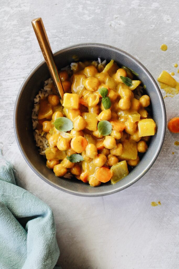 trader joes yellow curry in a gray bowl next to a teal napkin