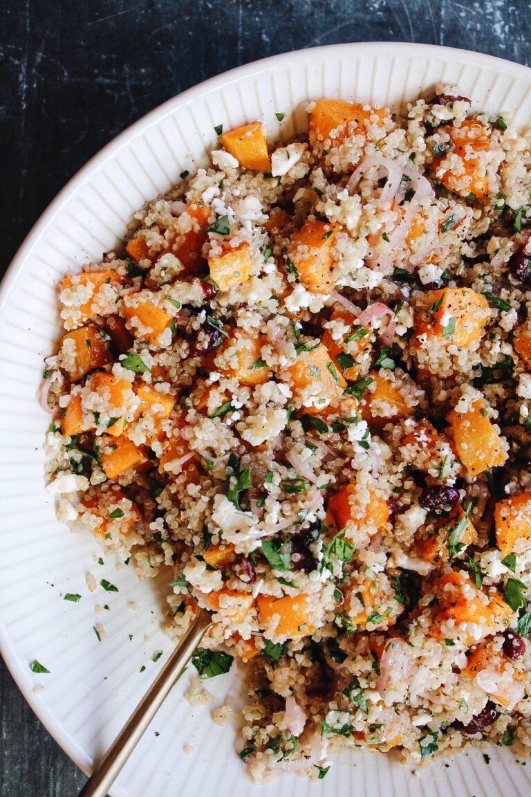 butternut squash quinoa salad in a beige bowl with gold serving spoon
