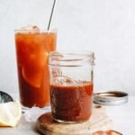 black tea concentrate in a small glass jar with a glass of iced tea behind it