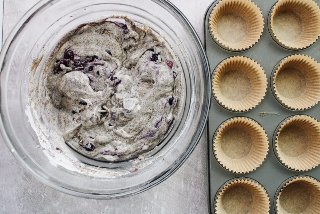 blueberry buckwheat muffins batter in a bowl next to a muffin tin