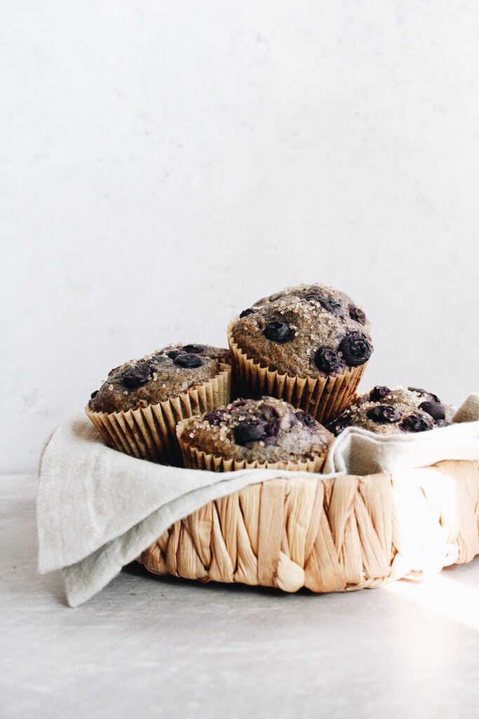blueberry buckwheat muffins in a strawbasket with a ray of sub hitting it