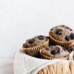 blueberry buckwheat muffins stacked in a straw basket