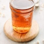 chamomile syrup in a glass jar on a wooden coaster