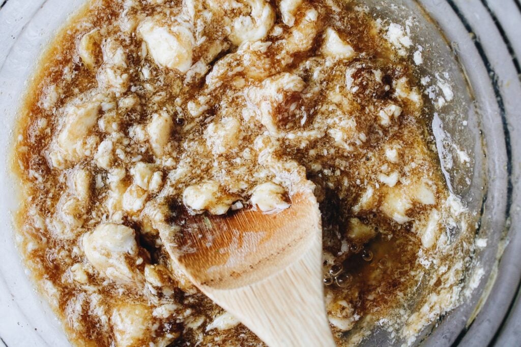 a wooden spoon stirring together honey, brown sugar, egg and butter
