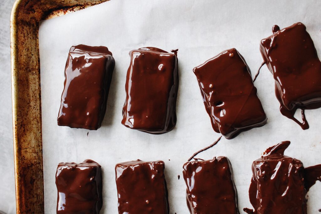chocolate dipped date bars on a baking sheet lined with parchment