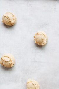 honey cookie dough dropped onto a parchment line baking sheet