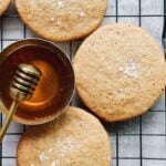 honey cookies with sea salt on a black wire cooling rack with a dish of honey