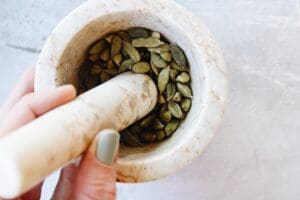 cardamom pods being ground with a mortar and pestle