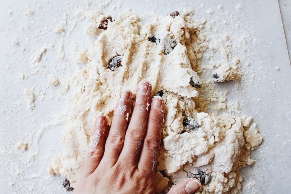 date scone dough being pressed down with a hand