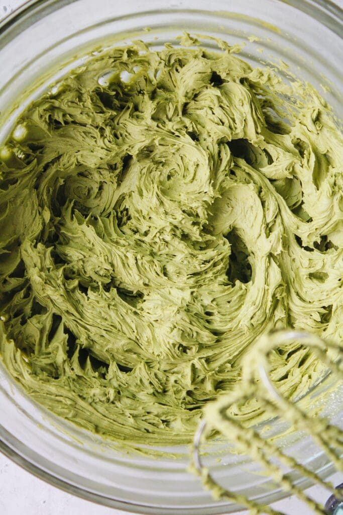 matcha frosting in a mixing bowl with an electric mixer