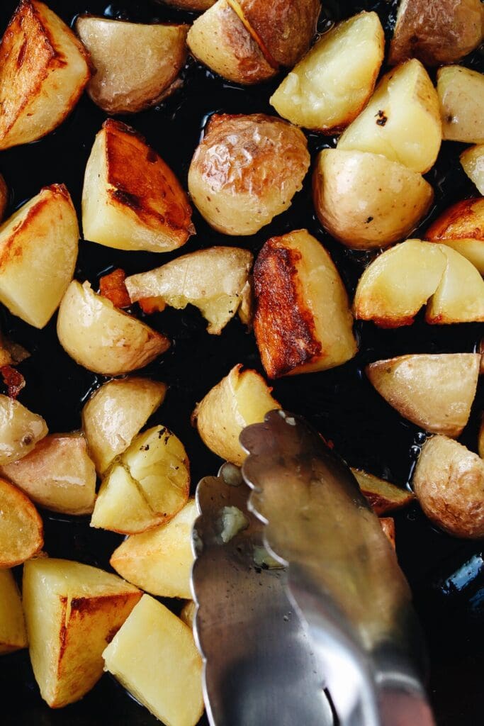 skillet fried potatoes being turned with tongs