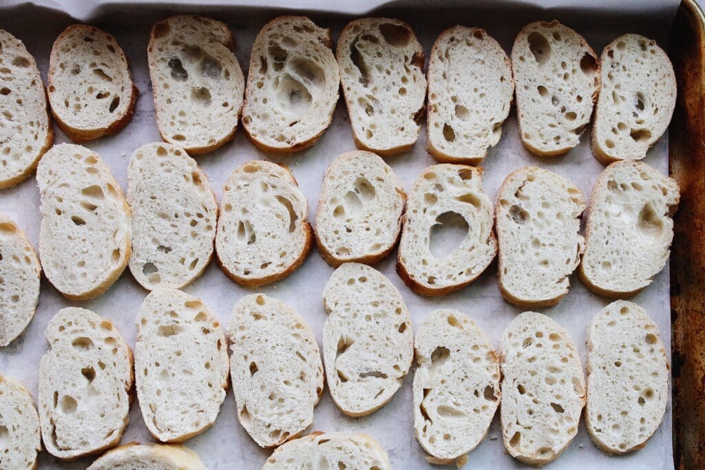 slices of a baguette on a baking sheet lined with parchment