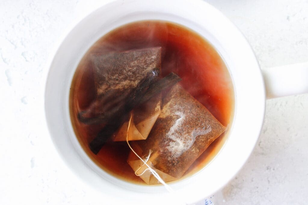 two black tea bags steeping in a mug