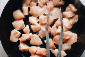 chicken breast cut into pieces cooking in a cast-iron skillet