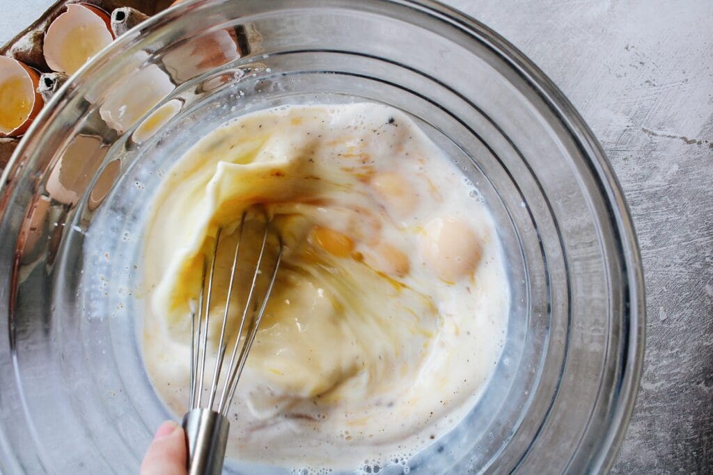 eggs and milk being whisked in a mixing bowl