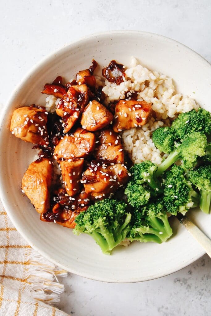 kumquat chicken in a white bowl with broccoli and rice