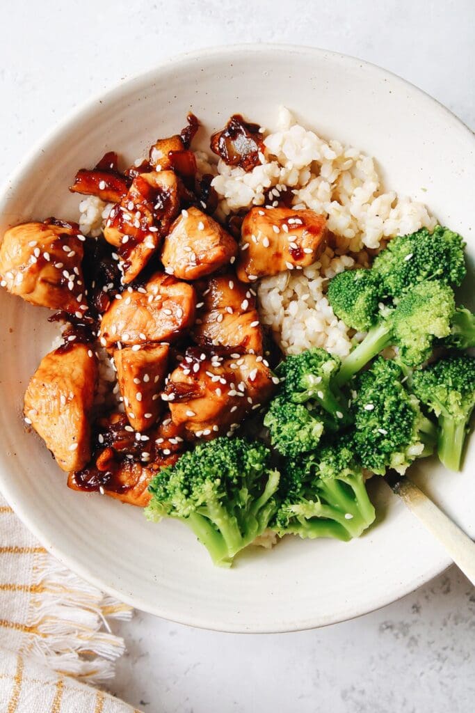 kumquat chicken in a white bowl with rice and broccoli