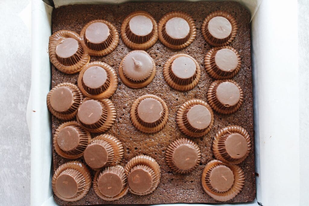 unwrapped peanut butter cups on top of hot brownies