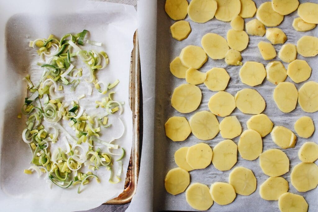 sliced leeks and thinly slice potatoes on two baking sheets