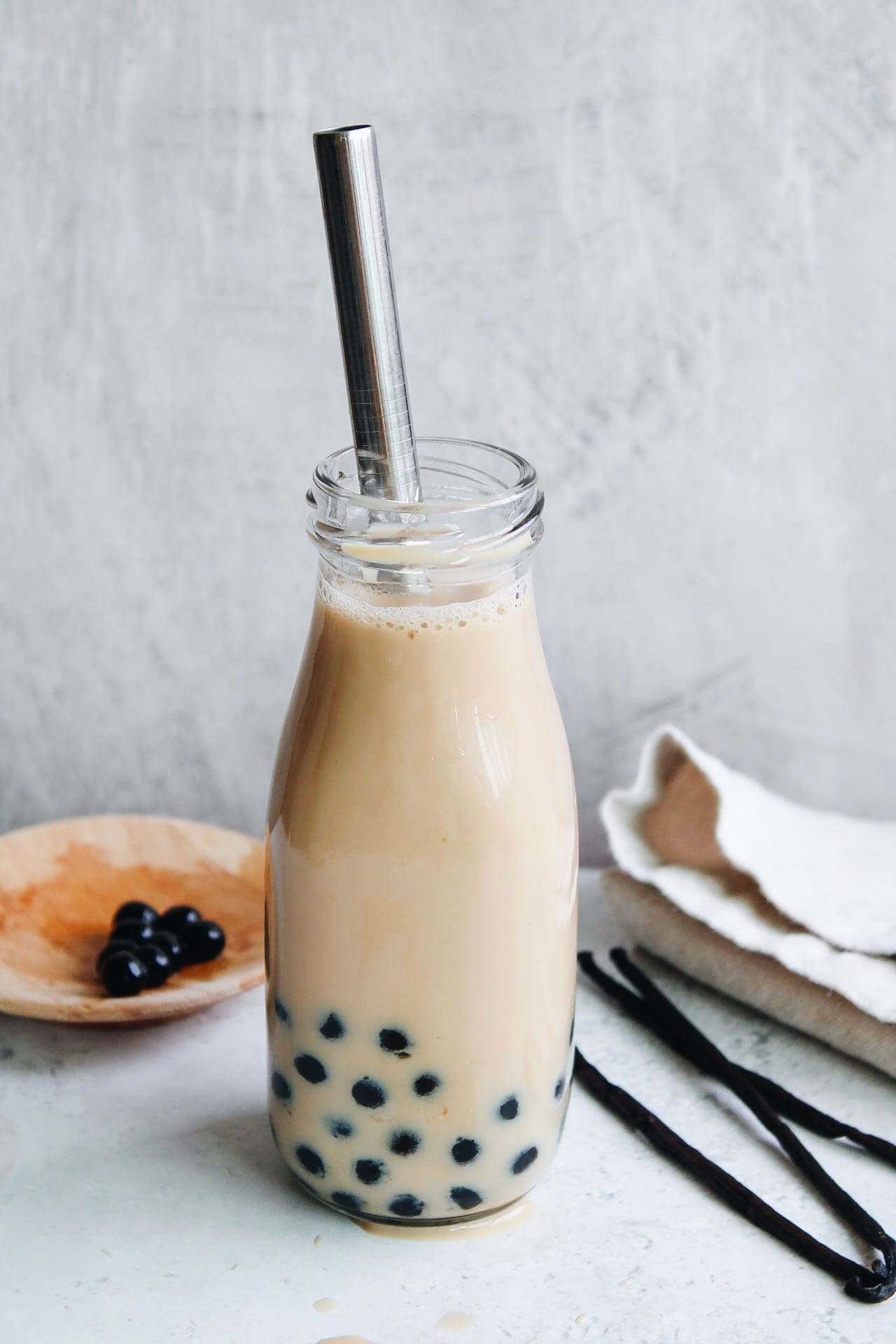 vanilla milk tea in a glass bottle with a metal straw