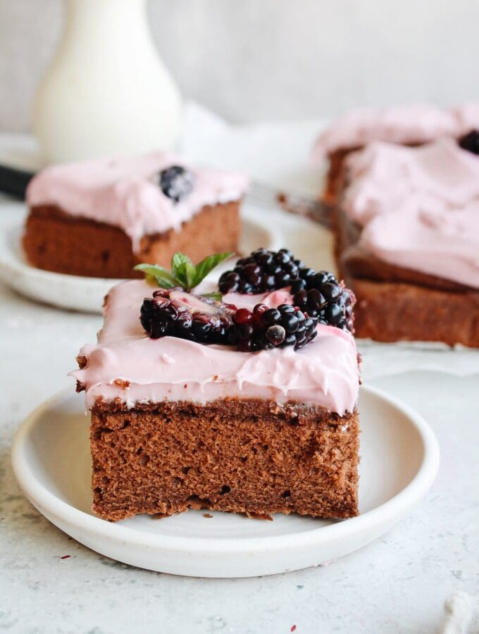 slice of blackberry chocolate cake with blackberry cream cheese frosting on a white plate