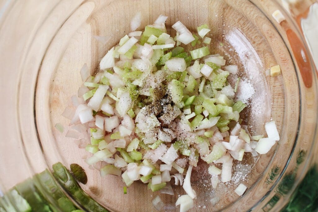 chopped celery and onions in a glass mixing bowl