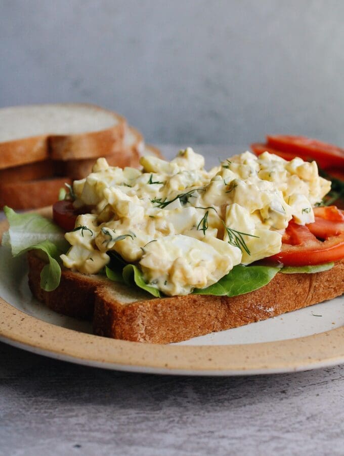 egg salad with pickles on bread with lettuce and tomato