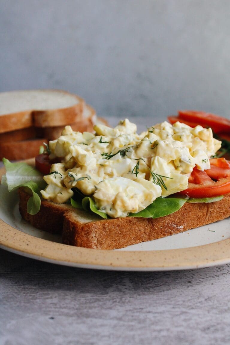 egg salad with pickles on bread with lettuce and tomato