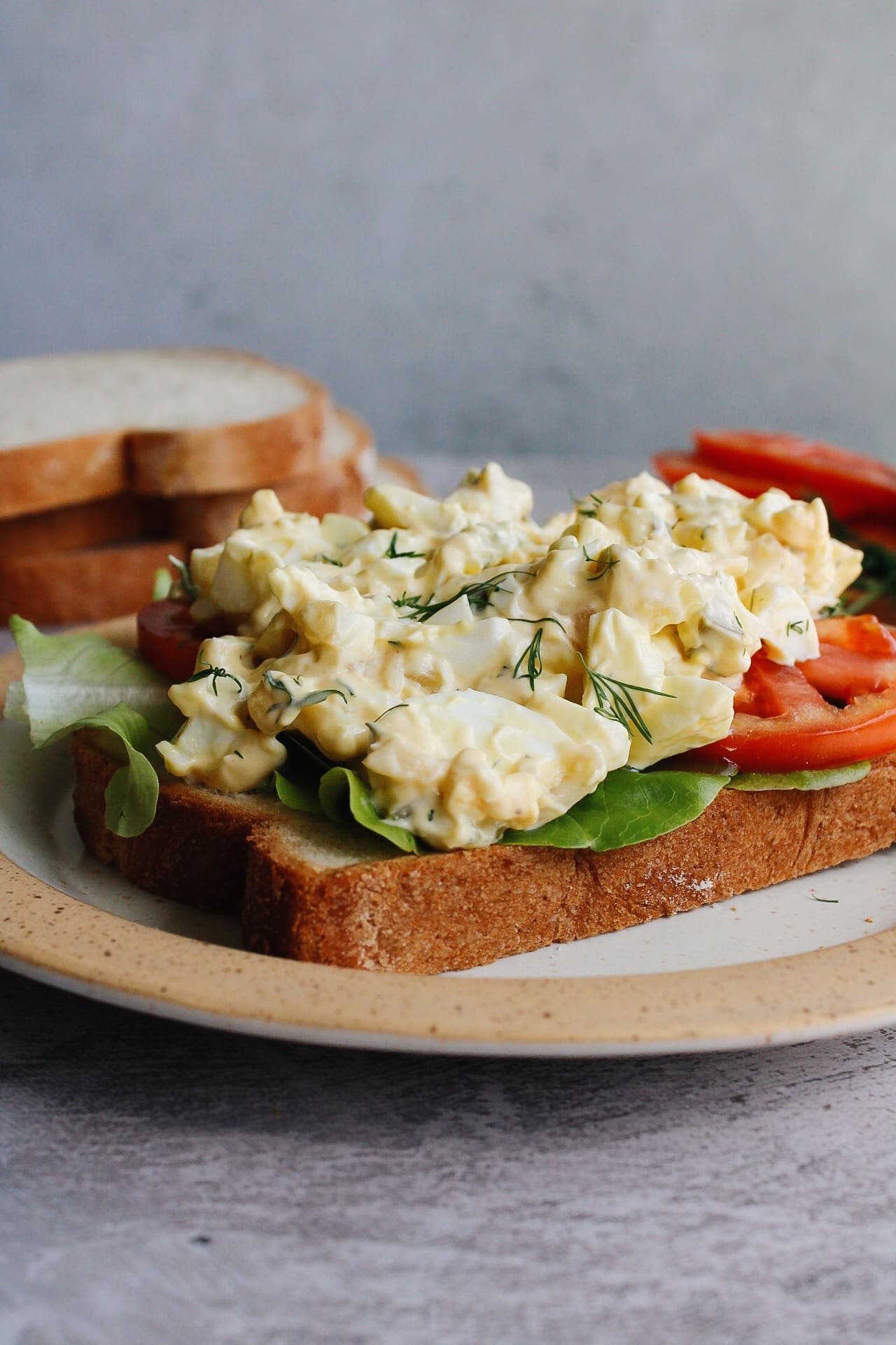 egg salad with pickles on a slice of bread with tomato and lettuce