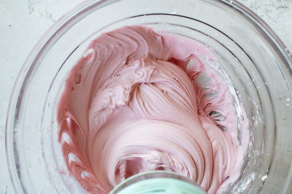 blackberry cream cheese frosting in a mixing bowl with electric beaters