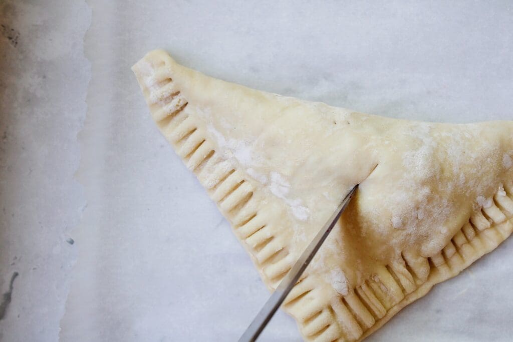 a small slit being cut in the top of a puff pastry turnover