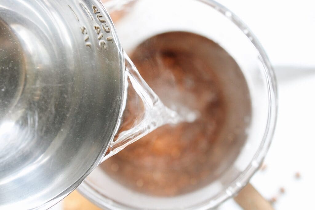 boiling water being poured over ground coffee in a french press