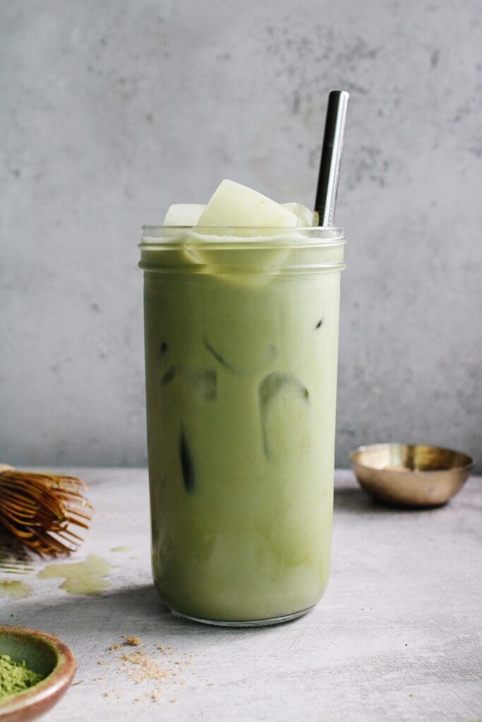 iced oat milk matcha latte in a clear glass 