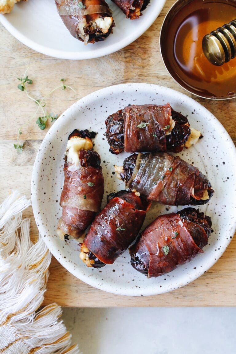 prosciutto wrapped dates on a white plate