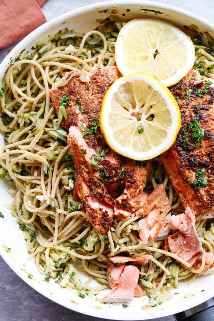 salmon fillets on veggie pasta garnished with lemon slices