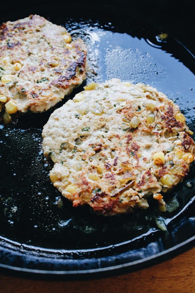 southwest chicken burgers cooking in a cast-iron skillet