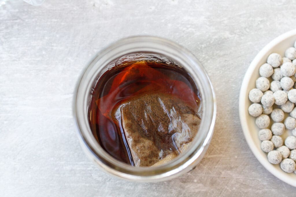 black tea bags steeping in a jar with boiling water