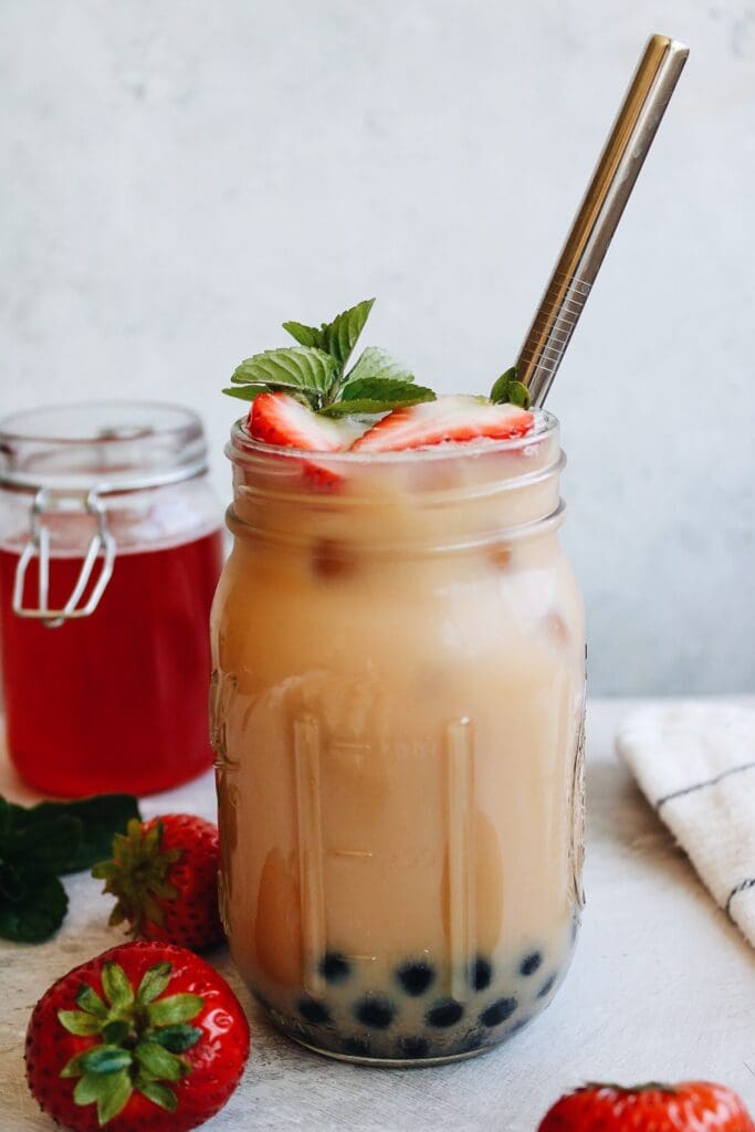 strawberry bubble tea in a glass jar with a boba straw