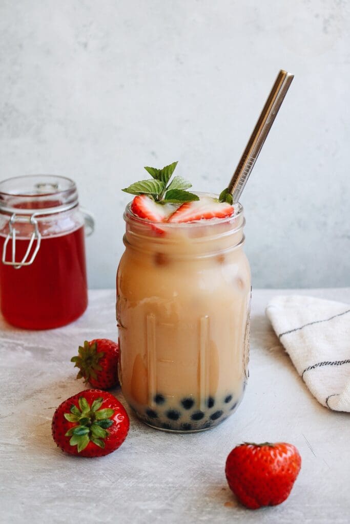 strawberry bubble tea in a mason jar with a straw and mint