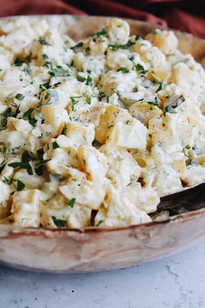 potato salad with pickles in a large bowl topped with parsley
