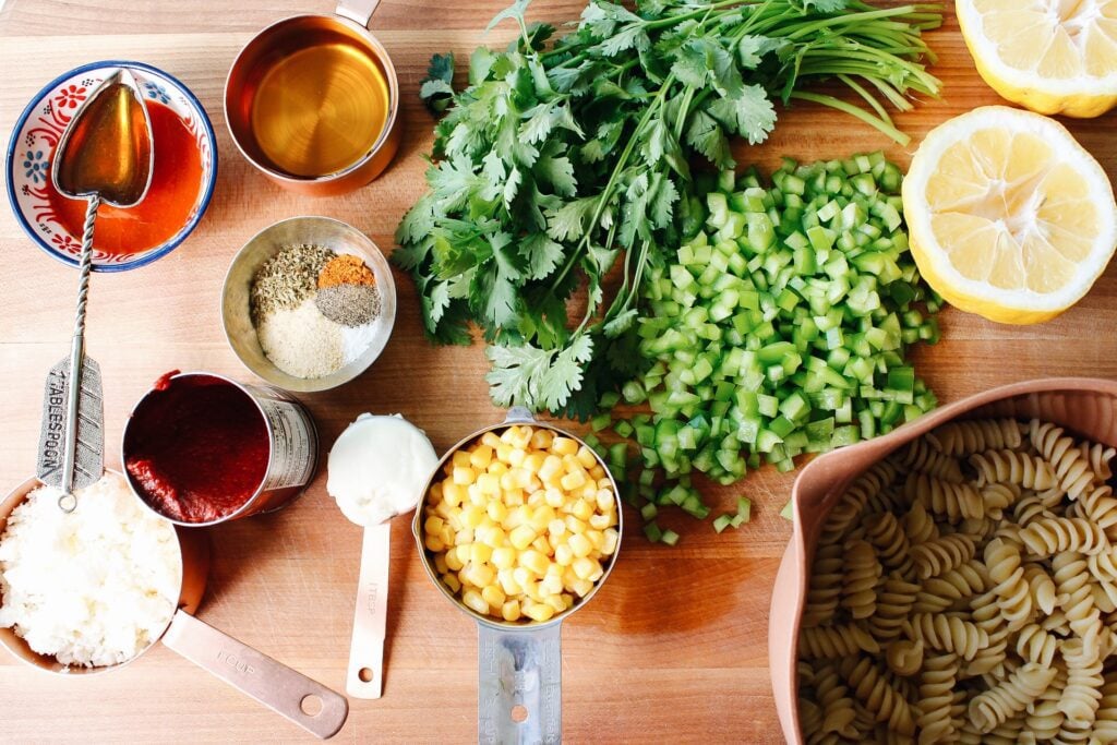 ingredients for spicy pasta salad on a wooden cutting board