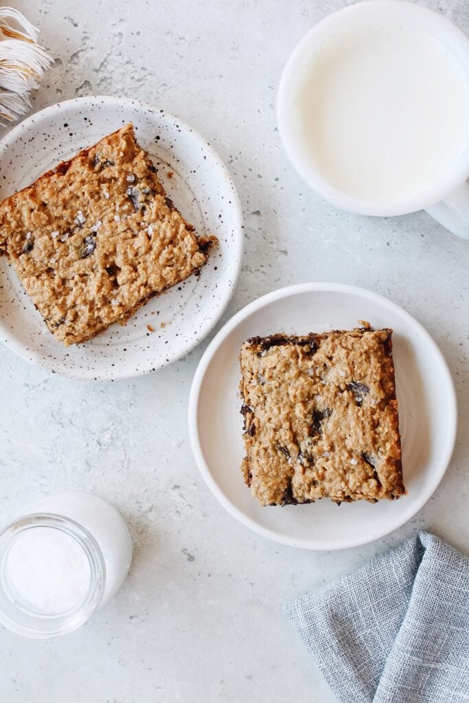 peanut butter oatmeal bars on white plates with a glass of milk