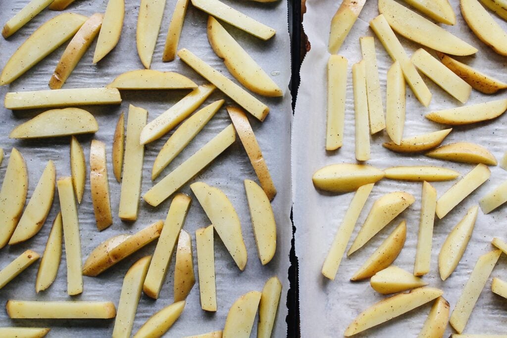 sliced potatoes on a baking sheet before baking
