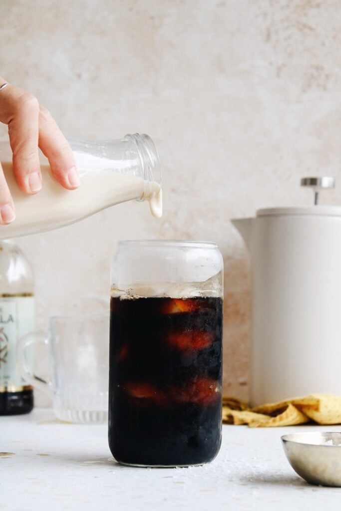 homemade coffee creamer being added to iced coffee
