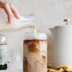 homemade coffee cream being poured into a glass of iced coffee