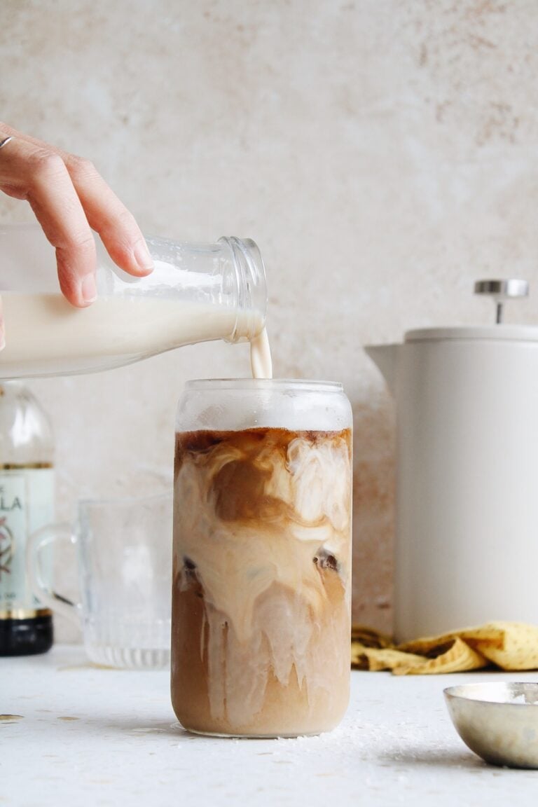 homemade coffee cream being poured into a glass of iced coffee